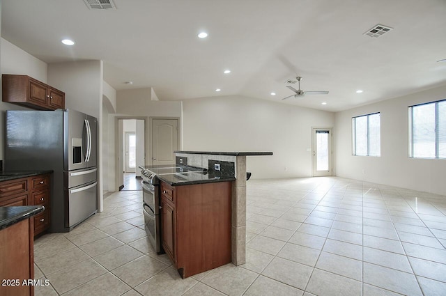 kitchen with a center island, light tile patterned floors, stainless steel appliances, open floor plan, and vaulted ceiling