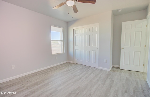 unfurnished bedroom with light wood-style flooring, a ceiling fan, baseboards, and a closet