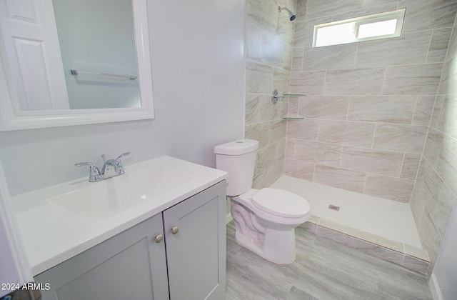 bathroom featuring tiled shower, toilet, vanity, and wood finished floors