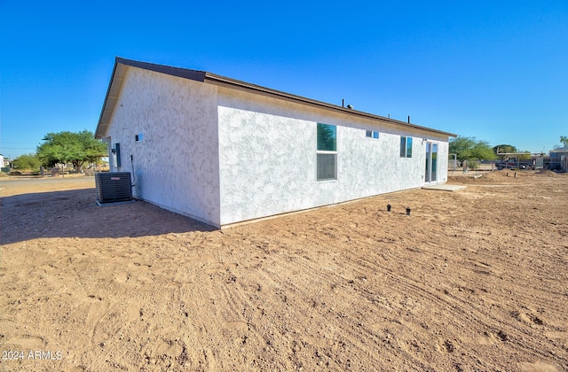 view of side of property with central AC unit and stucco siding