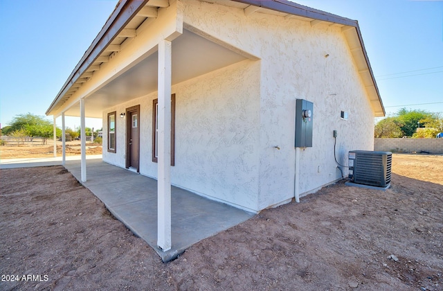 view of property exterior with stucco siding, cooling unit, and fence