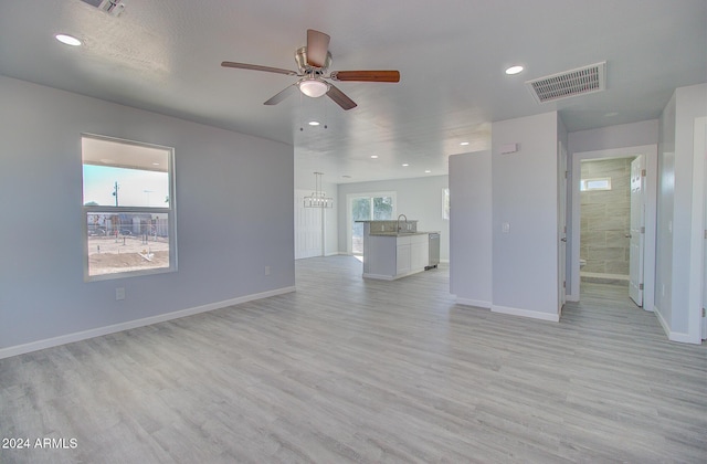 unfurnished living room featuring a sink, visible vents, baseboards, and light wood-style floors