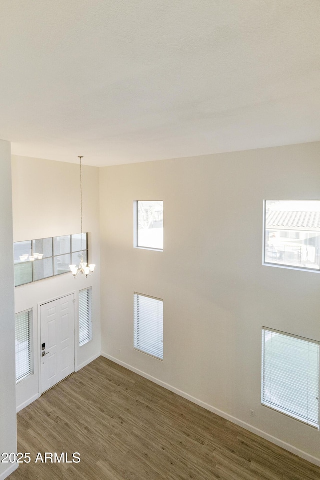 entrance foyer featuring a healthy amount of sunlight, dark wood-type flooring, a notable chandelier, and a towering ceiling