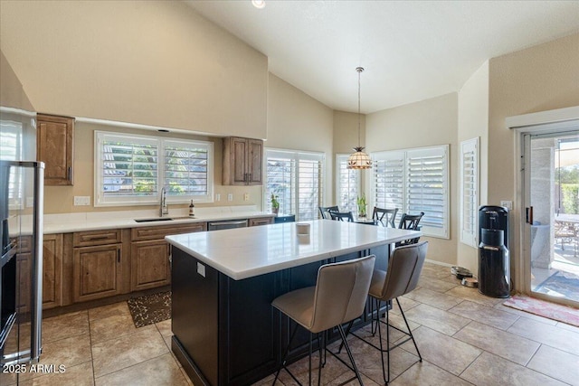 kitchen with brown cabinets, a breakfast bar area, light countertops, a kitchen island, and a sink