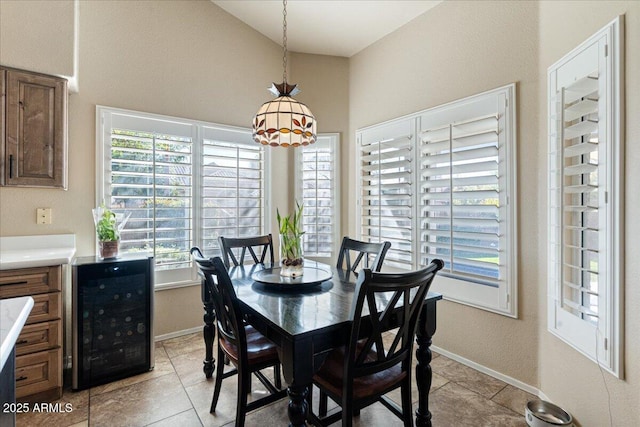 dining room with lofted ceiling, beverage cooler, baseboards, and light tile patterned flooring