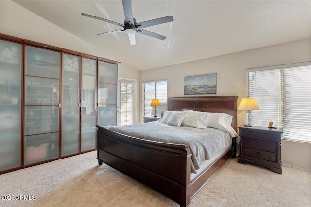 bedroom with multiple windows, vaulted ceiling, a ceiling fan, and light colored carpet