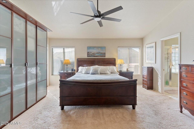 bedroom featuring lofted ceiling, ensuite bath, ceiling fan, carpet, and a textured ceiling