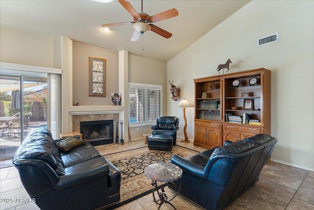 tiled living area with visible vents, ceiling fan, high vaulted ceiling, a tile fireplace, and baseboards