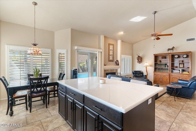 kitchen with a kitchen island, visible vents, hanging light fixtures, light countertops, and a tiled fireplace