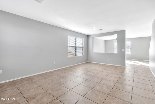 tiled spare room with ceiling fan and a healthy amount of sunlight