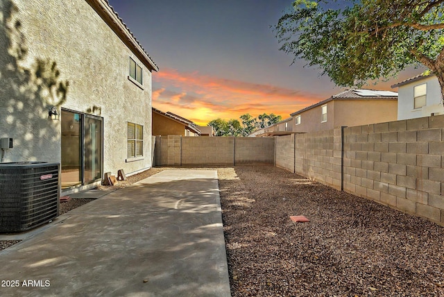 yard at dusk with a patio and central AC unit