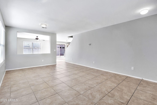 empty room featuring ceiling fan with notable chandelier and light tile patterned floors