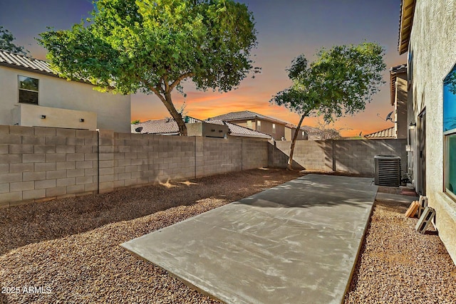 yard at dusk featuring a patio area and central air condition unit