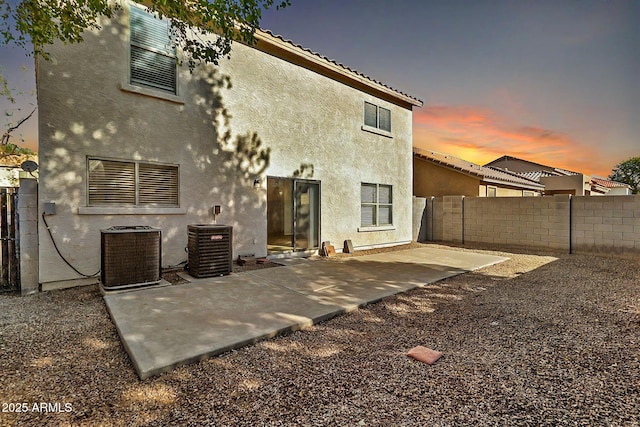 back house at dusk featuring a patio and cooling unit