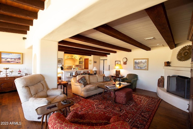 living room featuring beam ceiling, a large fireplace, and dark hardwood / wood-style floors