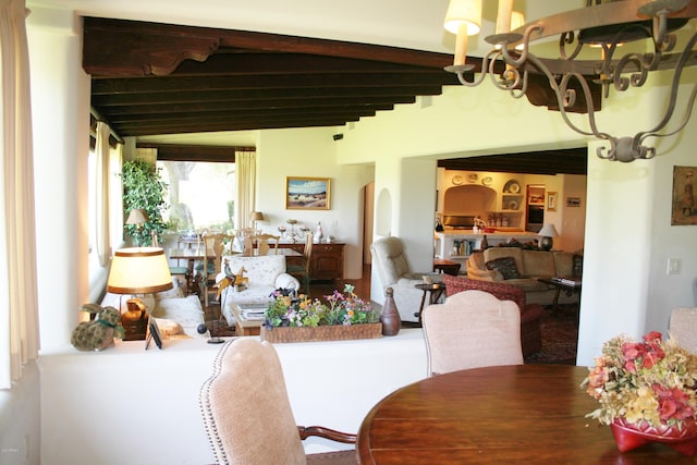 dining space with beamed ceiling and a notable chandelier
