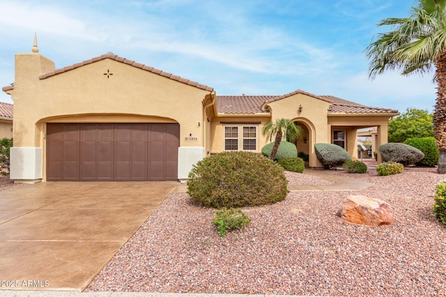 mediterranean / spanish-style house with concrete driveway, a tiled roof, an attached garage, and stucco siding