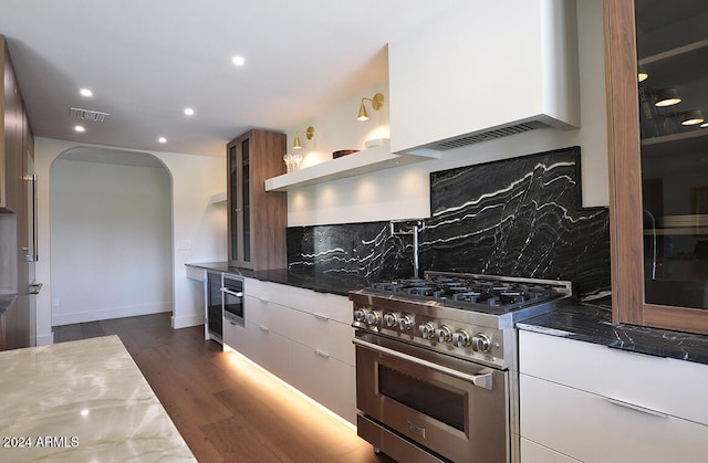 kitchen with white cabinets, dark hardwood / wood-style flooring, backsplash, and appliances with stainless steel finishes