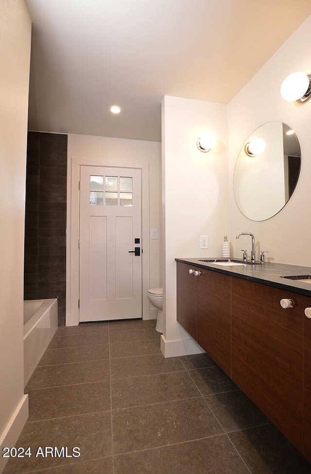 bathroom with a bathing tub, tile patterned flooring, vanity, and toilet