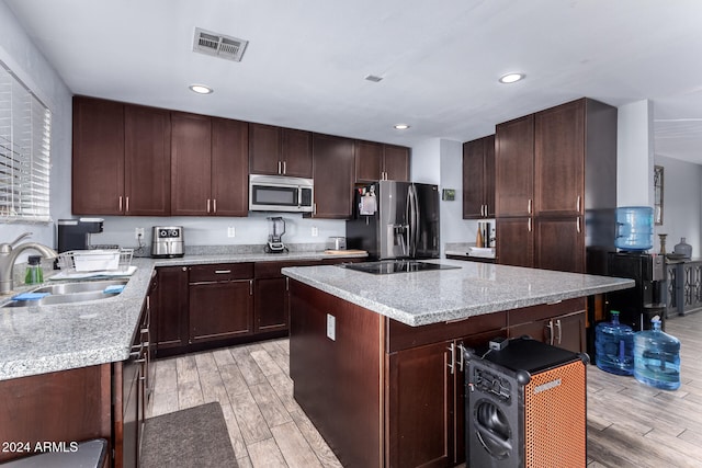 kitchen featuring stainless steel appliances, sink, light wood-type flooring, and a kitchen island