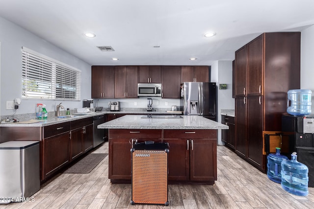 kitchen with stainless steel appliances, a center island, and light wood-type flooring