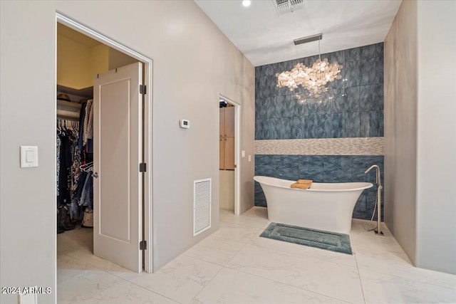 bathroom with tile walls, an inviting chandelier, and a bathing tub