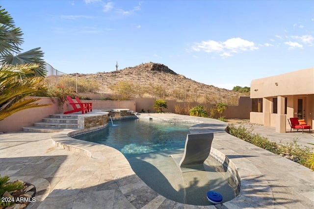 view of pool featuring pool water feature, a mountain view, and a patio