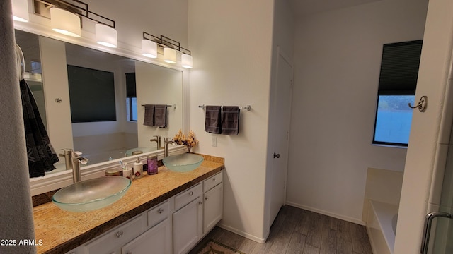 bathroom featuring a sink, a washtub, and wood finished floors