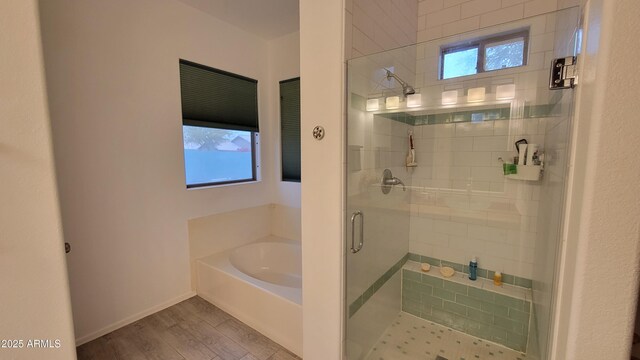 full bathroom with a shower stall, a bath, wood finished floors, and a wealth of natural light