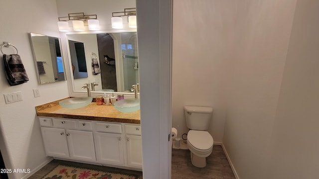 bathroom featuring a sink, baseboards, double vanity, and toilet