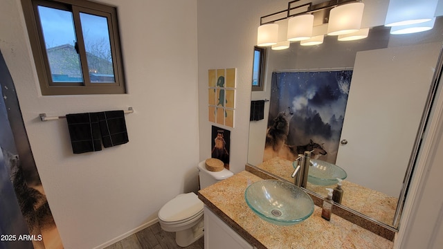 bathroom featuring vanity, toilet, curtained shower, wood finished floors, and baseboards