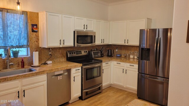 kitchen with appliances with stainless steel finishes, decorative backsplash, a sink, and ornamental molding