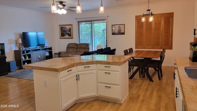 kitchen featuring open floor plan, light wood-style floors, ceiling fan, and ornamental molding