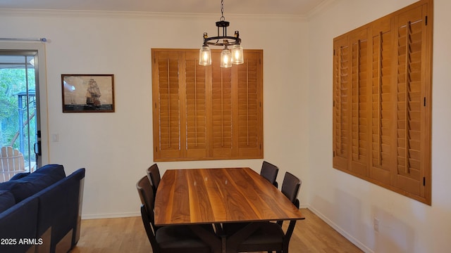dining room featuring crown molding, light wood finished floors, baseboards, and an inviting chandelier
