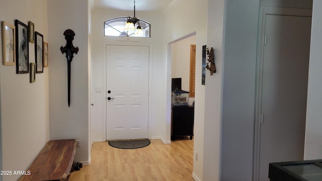 foyer with crown molding, baseboards, and light wood-type flooring