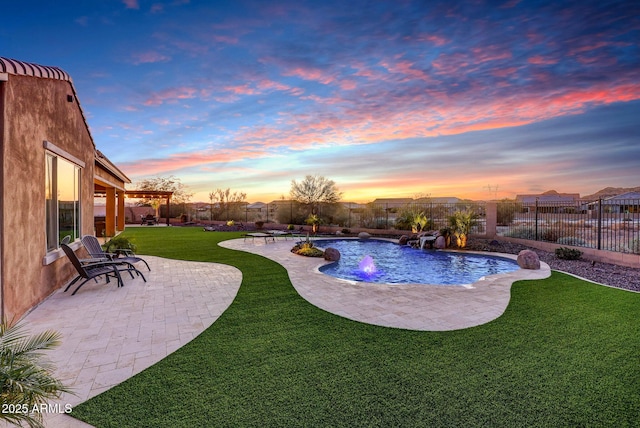 pool at dusk featuring pool water feature, a yard, and a patio