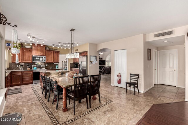 dining room featuring arched walkways, baseboards, and visible vents