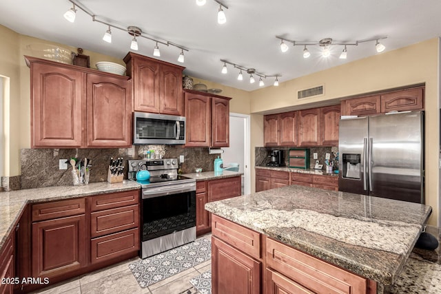 kitchen featuring light stone countertops, tasteful backsplash, appliances with stainless steel finishes, light tile patterned floors, and visible vents