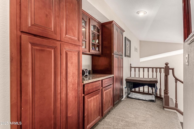 interior space featuring baseboards, lofted ceiling, and light colored carpet
