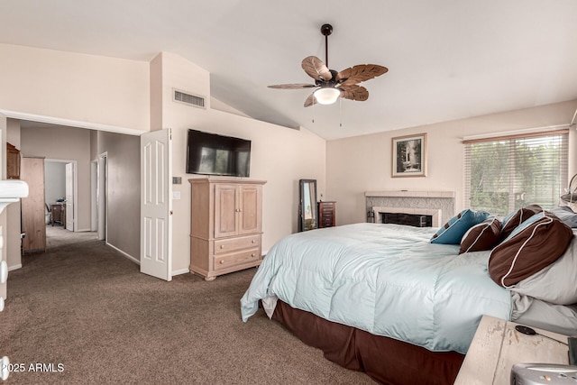 bedroom featuring vaulted ceiling, a fireplace, dark colored carpet, baseboards, and visible vents