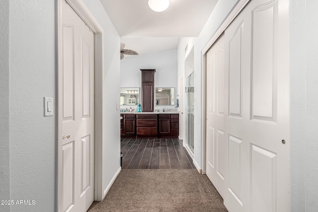 hallway featuring dark wood finished floors, dark carpet, and a sink