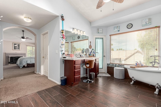 bar with lofted ceiling, baseboards, a ceiling fan, a fireplace, and wood tiled floor