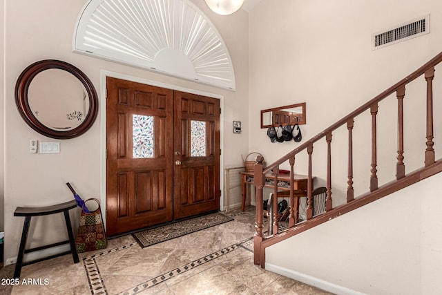 entrance foyer with baseboards, stairs, and visible vents