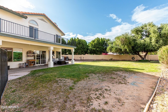 view of yard featuring a balcony, a fenced backyard, and a patio area