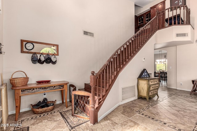 staircase featuring baseboards, visible vents, and a towering ceiling