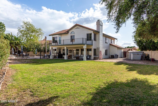 rear view of property featuring a balcony, stucco siding, fence, and a chimney