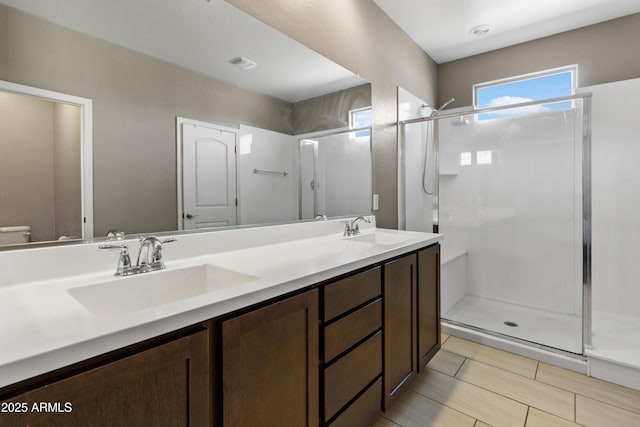 bathroom featuring double vanity, a sink, visible vents, and a shower stall