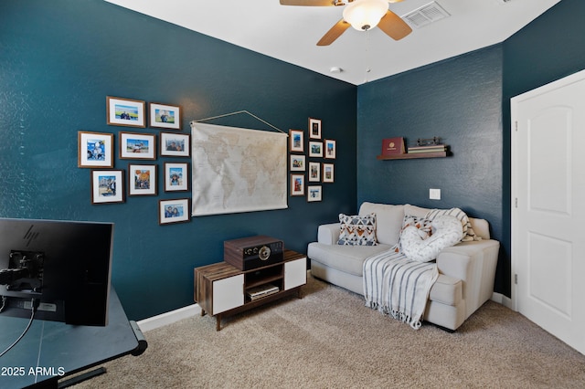 living room featuring visible vents, a textured wall, carpet flooring, ceiling fan, and baseboards