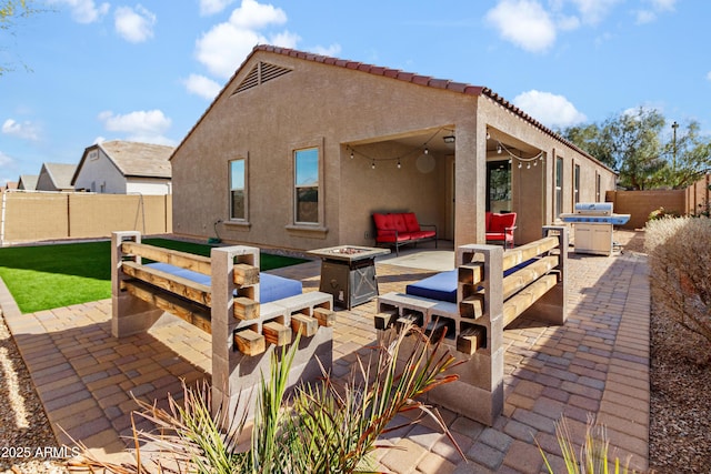 back of property with a fire pit, a patio, a fenced backyard, and stucco siding