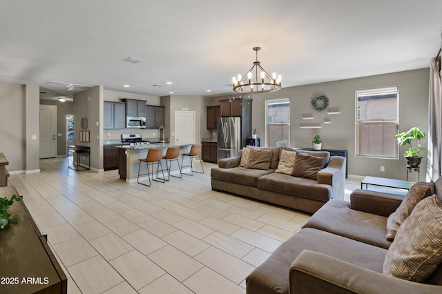 living area with light tile patterned floors, recessed lighting, visible vents, a chandelier, and baseboards